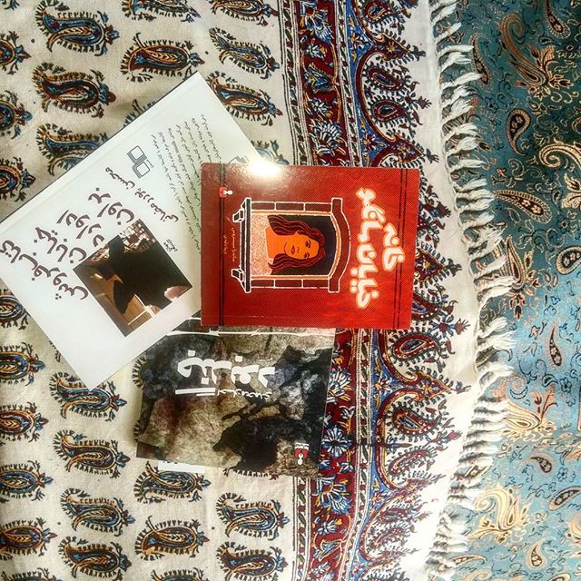 نگاره:  اگر هنوز برای عزیزانتان عیدی نخریده‌اید و نمی‌دانید چه بخرید این دو پیشنهاد و به ویژه ترکیبشان را از دست ندهید: ۱) کتاب بخرید. اگر هم نمی‌دانید چه کتابی بخرید، همین‌ها که توی عکس می‌بینید خوبند، شک نکنید، اگر پول کتاب خریدن ندارید بیایید همین‌ها را از من و لادن عیدی بگیرید ۲) رزرو یک روز اقامت در اتاق کرسی خانه روحانی برزک را عیدی بدهید تا مخاطب خاص‌تان بلمد زیر کرسی و کتاب‌های بند اول را بخواند کیفور از پس‌زمینه‌ای که از پنجره پیداست: کوه و آسمان آبی و ابر سفید و شکوفه‌ها و درختان